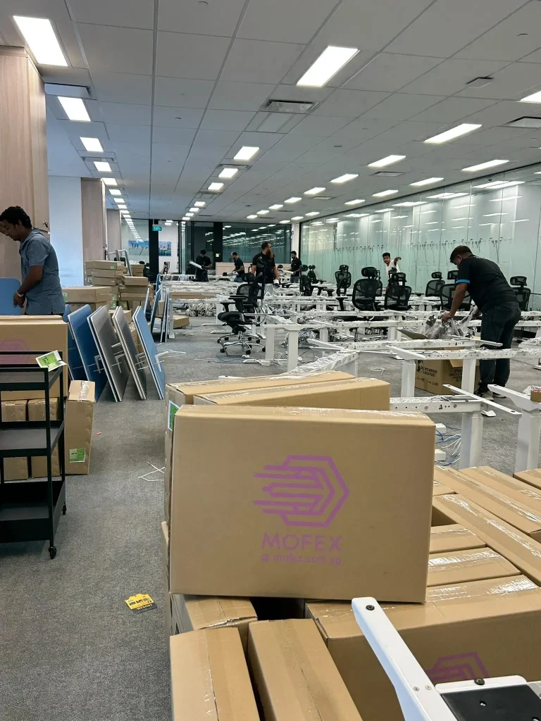 Mofex crew relocating desks and cartons across an open-plan office